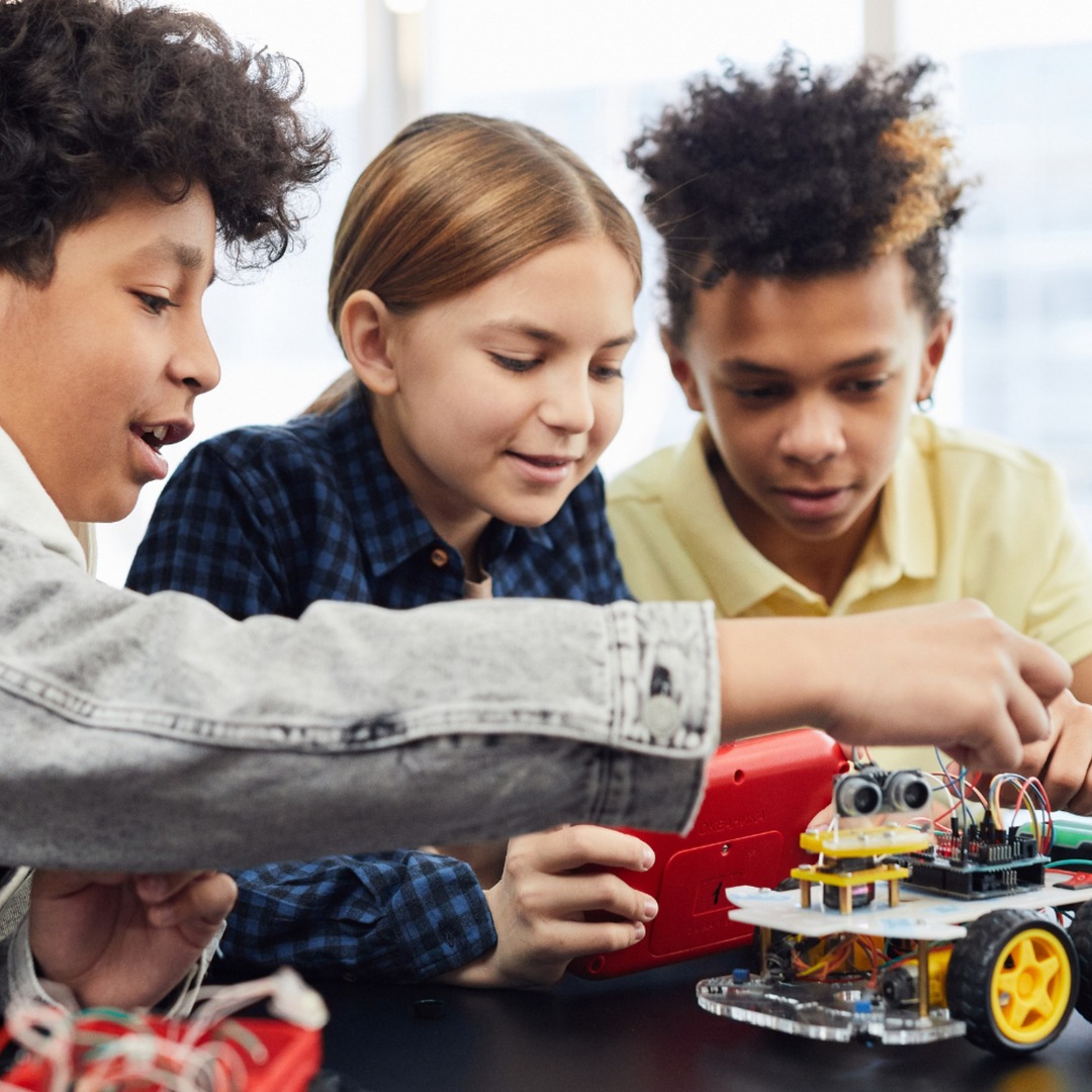 Imagen de portada de curso "Aprendizaje Basado en Proyectos con foco en robótica" - Se visualizan 1 Chica y 2 Chicos trabajando sobre una pieza robótica.