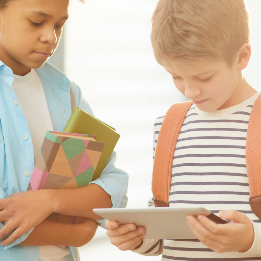 Imagen de portada de curso "Tendencias culturales y tecnologías emergentes" - Se visualizan dos chicos con mochilas colgando, observando la pantalla de una tablet